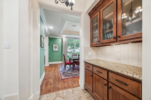 5418 Braeburn Dr, Bellaire, TX 77401 - kitchen featuring ornamental molding, brown cabinets, baseboards, glass insert cabinets, and light stone countertops