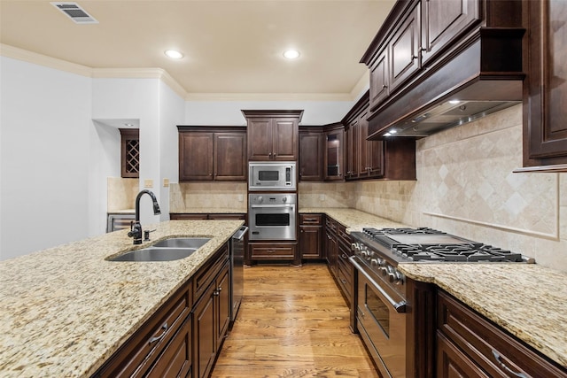 2403 Commonwealth St, Houston, TX 77006 - kitchen featuring appliances with stainless steel finishes, a sink, dark brown cabinetry, light stone countertops, and crown molding