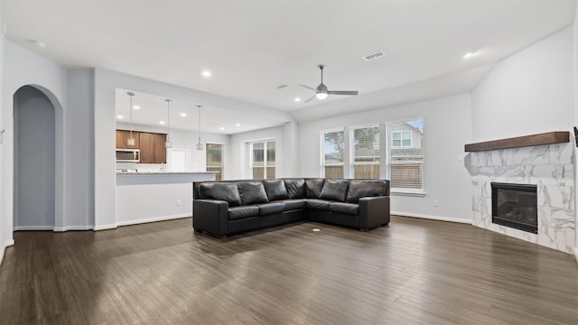 18010 Wagstaff Way, Richmond, TX 77407 - living area with dark wood-style floors, a ceiling fan, a high end fireplace, arched walkways, and baseboards