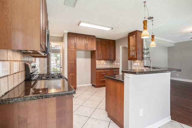 311 Vantage Pointe Cir, League City, TX 77573 - kitchen with stainless steel range with gas stovetop, brown cabinets, crown molding, a peninsula, and tasteful backsplash