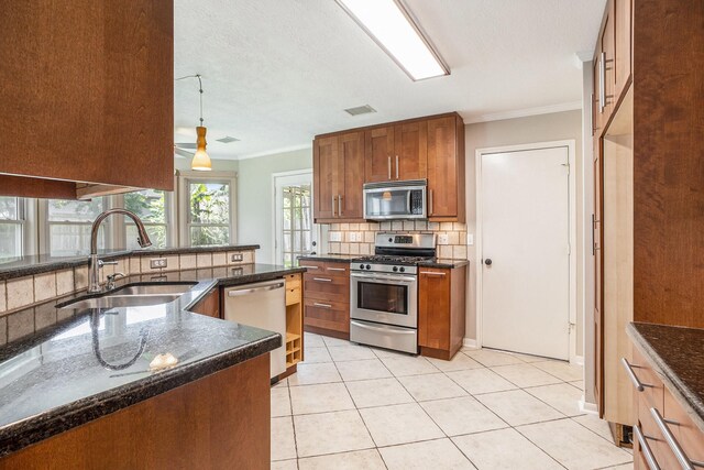 311 Vantage Pointe Cir, League City, TX 77573 - kitchen with stainless steel appliances, a sink, tasteful backsplash, brown cabinetry, and crown molding