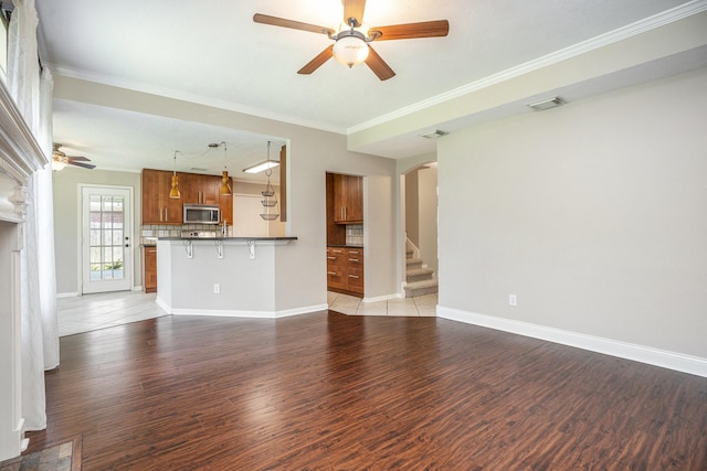 311 Vantage Pointe Cir, League City, TX 77573 - unfurnished living room featuring a ceiling fan, crown molding, light wood-style floors, arched walkways, and baseboards