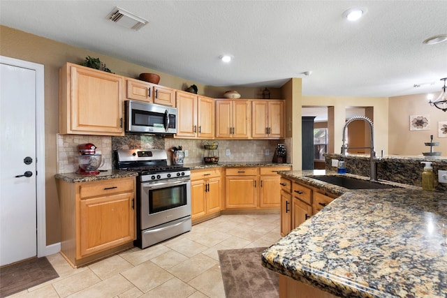 3803 Shiloh Park Ct, Friendswood, TX 77546 - kitchen featuring stainless steel appliances, a sink, tasteful backsplash, light brown cabinetry, and a textured ceiling