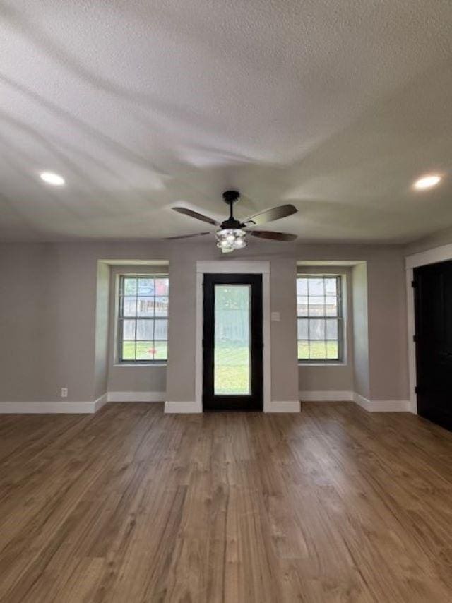 674 Meadowgreen Dr, Port Neches, TX 77651 - unfurnished living room with healthy amount of natural light, a textured ceiling, wood finished floors, a ceiling fan, and baseboards