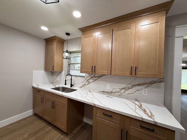 674 Meadowgreen Dr, Port Neches, TX 77651 - kitchen featuring a sink, decorative backsplash, wood finished floors, light stone counters, and recessed lighting