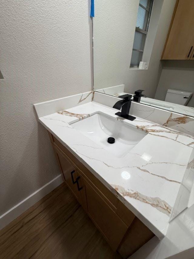 674 Meadowgreen Dr, Port Neches, TX 77651 - bathroom featuring wood finished floors, vanity, baseboards, a textured wall, and toilet