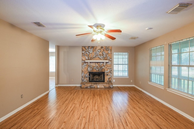 1083 County Rd 147, Alvin, TX 77511 - unfurnished living room featuring light wood-style flooring, ceiling fan, baseboards, and a stone fireplace