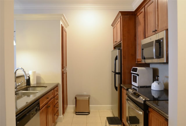 2203 Dorrington St Unit 403, Houston, TX 77030 - kitchen featuring stainless steel appliances, a sink, light tile patterned flooring, baseboards, and dark stone countertops