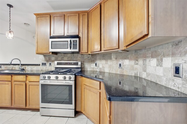 9210 E Lakeside Dr, Magnolia, TX 77354 - kitchen featuring stainless steel appliances, a sink, backsplash, light tile patterned floors, and hanging light fixtures