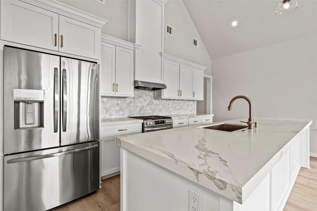 1104 62nd St, Galveston, TX 77551 - kitchen featuring stainless steel appliances, a sink, light wood-style flooring, tasteful backsplash, and a center island with sink