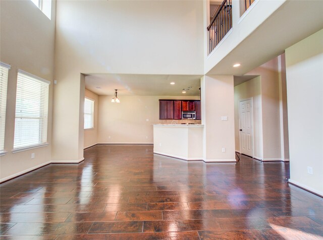 9110 Darby Park Ln, Richmond, TX 77407 - unfurnished living room featuring a towering ceiling, dark wood finished floors, and a chandelier