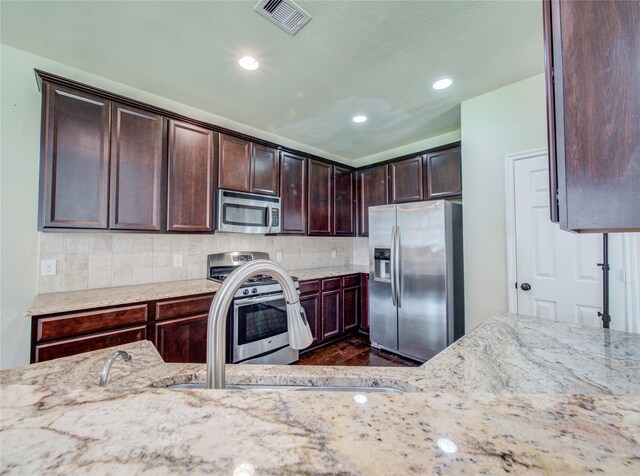 9110 Darby Park Ln, Richmond, TX 77407 - kitchen with appliances with stainless steel finishes, light stone countertops, tasteful backsplash, dark brown cabinets, and recessed lighting