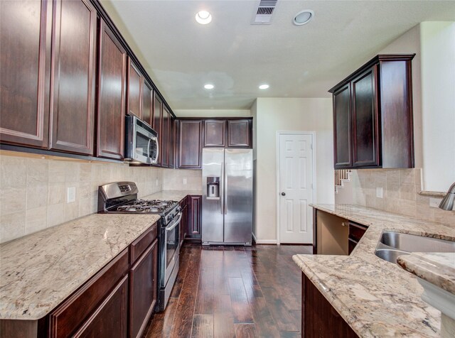 9110 Darby Park Ln, Richmond, TX 77407 - kitchen featuring stainless steel appliances, light stone countertops, recessed lighting, dark wood-type flooring, and dark brown cabinets