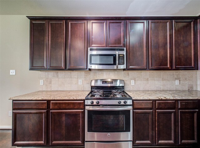 9110 Darby Park Ln, Richmond, TX 77407 - kitchen with appliances with stainless steel finishes, backsplash, light stone countertops, and dark brown cabinetry