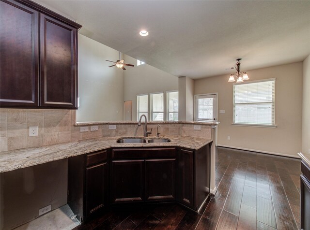 9110 Darby Park Ln, Richmond, TX 77407 - kitchen featuring a peninsula, tasteful backsplash, a chandelier, dark wood-type flooring, and light stone counters