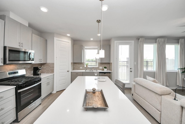 10053 Cloud Mist Dr, Houston, TX 77080 - kitchen with stainless steel appliances, open floor plan, a sink, light wood-style floors, and backsplash