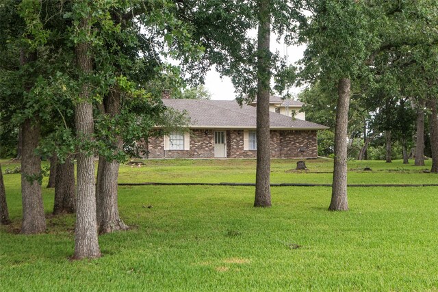 5150 Sandy Creek Ln, Brenham, TX 77833 - single story home with a front yard, brick siding, a shingled roof, and a chimney
