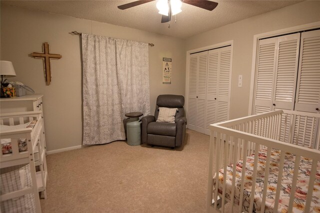 5150 Sandy Creek Ln, Brenham, TX 77833 - carpeted bedroom featuring multiple closets, a crib, a textured ceiling, a ceiling fan, and baseboards