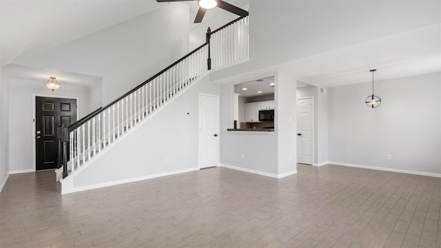 10811 Waterfern Ct, Houston, TX 77064 - unfurnished living room with ceiling fan, wood finished floors, baseboards, a high ceiling, and stairs