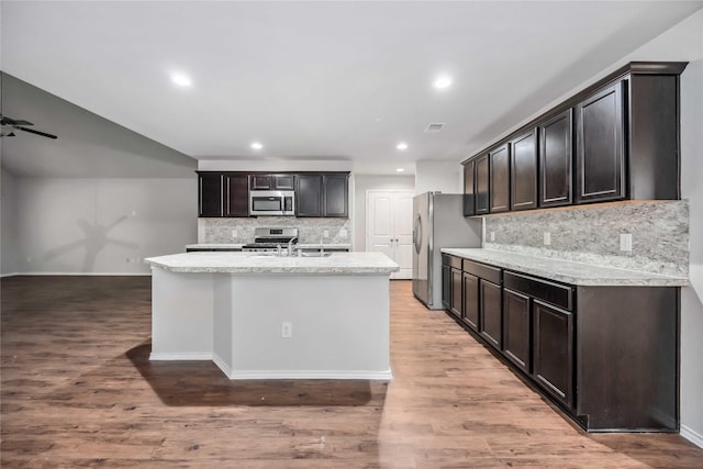 5627 Rainflower Terrace Ln, Spring, TX 77389 - kitchen with stainless steel appliances, backsplash, recessed lighting, light wood-style floors, and an island with sink