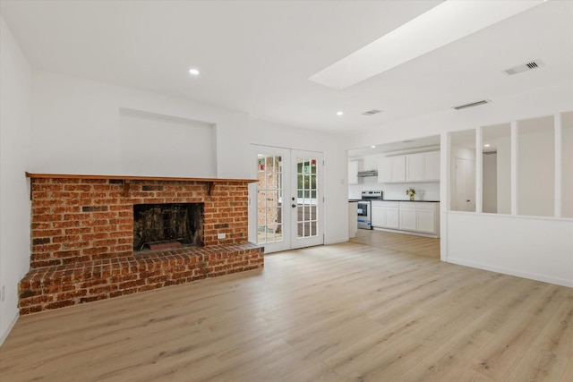 5511 Hickory Forest Dr, Houston, TX 77088 - unfurnished living room with light wood-type flooring, french doors, a skylight, recessed lighting, and a brick fireplace