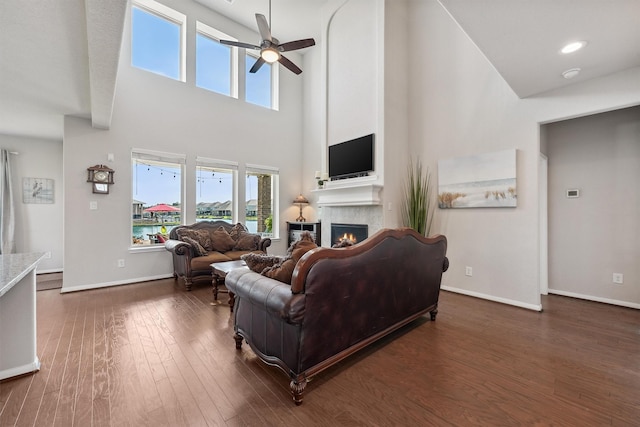 3651 Lake Bend Shore Dr, Spring, TX 77386 - living room with a lit fireplace, ceiling fan, dark wood finished floors, a high ceiling, and baseboards