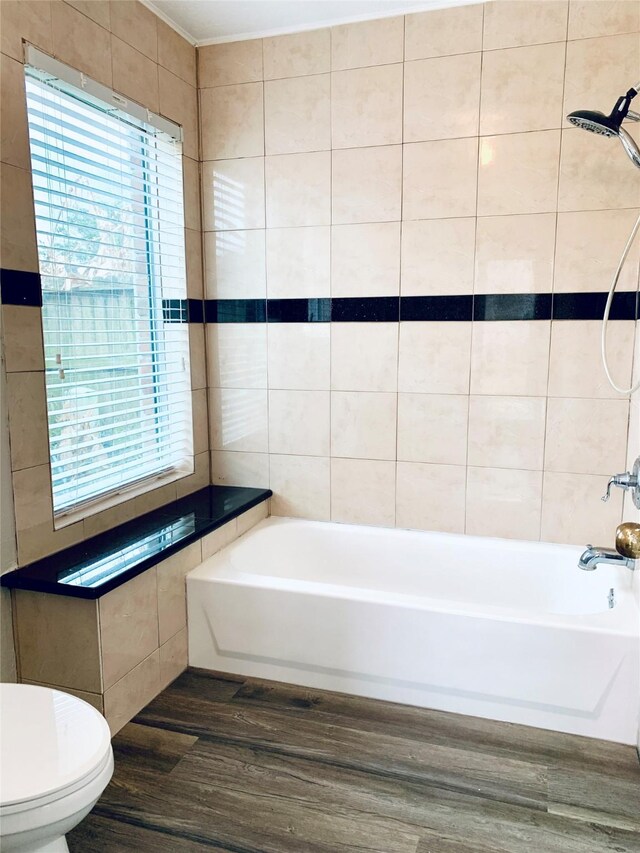 223 Kings Way, Stafford, TX 77477 - bathroom featuring wood finished floors, healthy amount of natural light, toilet, tile walls, and  shower combination
