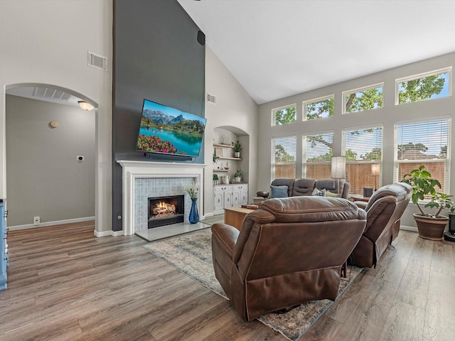 19122 High Canyon Ln, Tomball, TX 77377 - living area featuring high vaulted ceiling, arched walkways, wood finished floors, a fireplace, and baseboards