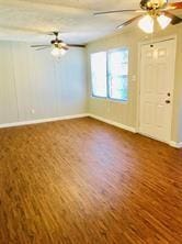 7725 St Lo Rd, Houston, TX 77033 - unfurnished living room with baseboards and dark wood finished floors