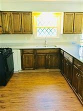 7725 St Lo Rd, Houston, TX 77033 - kitchen featuring a sink, stove, light wood-style floors, and light countertops