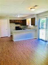 7725 St Lo Rd, Houston, TX 77033 - kitchen featuring wood finished floors, a peninsula, dark brown cabinetry, range, and baseboards