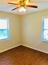 7725 St Lo Rd, Houston, TX 77033 - empty room featuring dark wood-type flooring, baseboards, and a ceiling fan