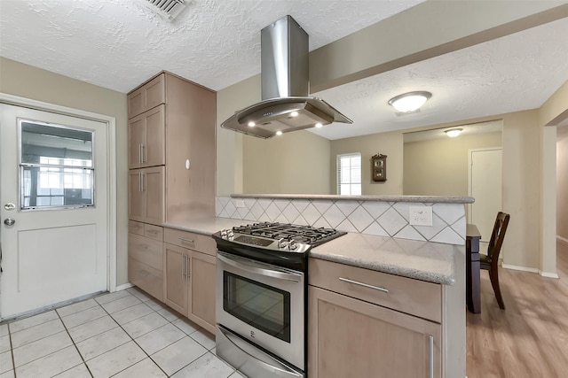 402 E Lambuth Ln, Deer Park, TX 77536 - kitchen with island range hood, gas range, a peninsula, decorative backsplash, and a textured ceiling