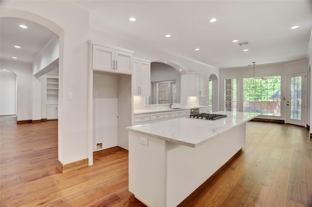 13502 Winter Creek Ct, Houston, TX 77077 - kitchen featuring a sink, white cabinets, light wood-style flooring, a center island, and arched walkways