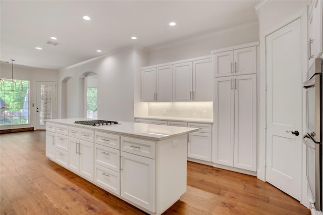 13502 Winter Creek Ct, Houston, TX 77077 - kitchen featuring stainless steel gas cooktop, crown molding, white cabinets, a kitchen island, and light wood-type flooring