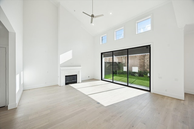 1139 Castellina Ln, Houston, TX 77055 - unfurnished living room with high vaulted ceiling, a glass covered fireplace, ceiling fan, and light wood-style floors