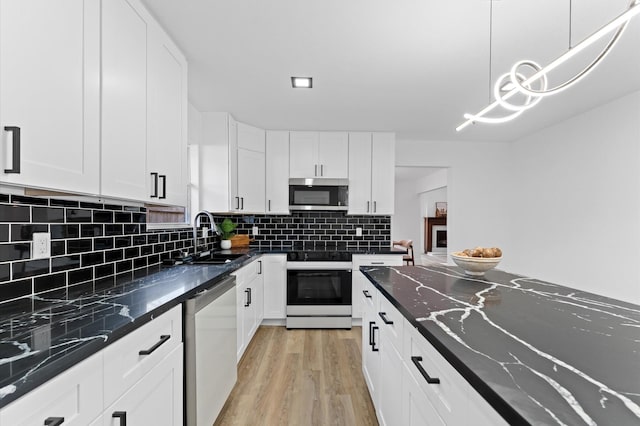 5507 Council Grove Ln, Houston, TX 77088 - kitchen with stainless steel appliances, a sink, light wood-type flooring, white cabinets, and decorative backsplash