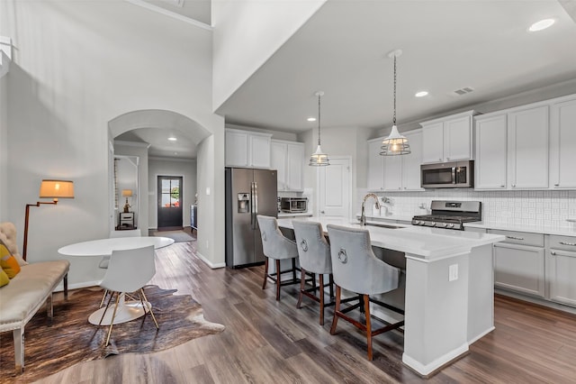 15818 Grampian Reach Ln, Humble, TX 77346 - kitchen with stainless steel appliances, arched walkways, an island with sink, backsplash, and light countertops