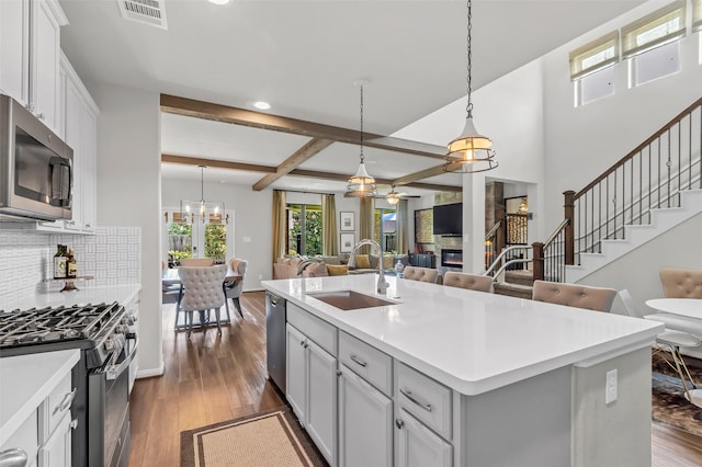 15818 Grampian Reach Ln, Humble, TX 77346 - kitchen with appliances with stainless steel finishes, open floor plan, a center island with sink, light countertops, and dark wood-style floors