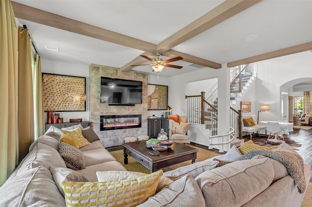 15818 Grampian Reach Ln, Humble, TX 77346 - living area featuring a tiled fireplace, stairway, arched walkways, wood finished floors, and beam ceiling