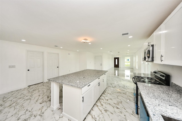 80 Rd 5608, Cleveland, TX 77327 - kitchen with black electric range, stainless steel microwave, a center island, white cabinetry, and light marble finish flooring
