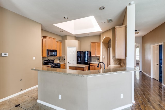 2803 Youpon Glen Way, Fresno, TX 77545 - kitchen with black appliances, arched walkways, a skylight, backsplash, and baseboards
