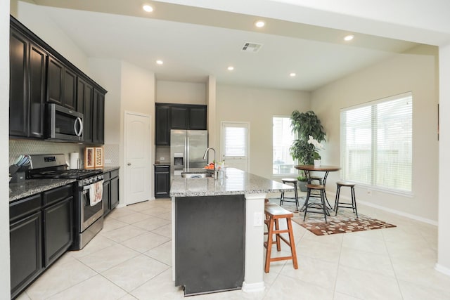 24710 Royal Pike Dr, Katy, TX 77493 - kitchen featuring stainless steel appliances, a sink, an island with sink, light stone counters, and decorative backsplash