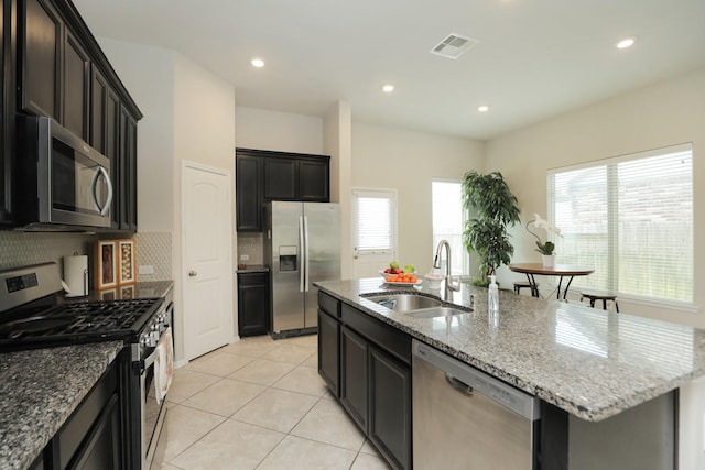 24710 Royal Pike Dr, Katy, TX 77493 - kitchen featuring appliances with stainless steel finishes, a sink, a kitchen island with sink, light stone countertops, and recessed lighting