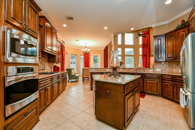 902 Delford Way, Sugar Land, TX 77479 - kitchen featuring appliances with stainless steel finishes, crown molding, a peninsula, backsplash, and plenty of natural light