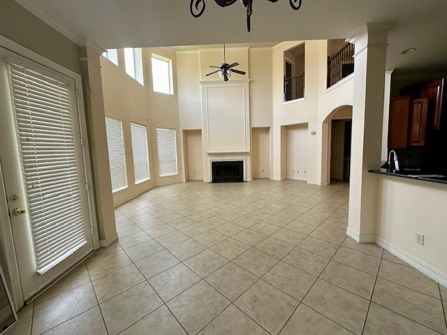 3003 Mystic Frst, Missouri City, TX 77459 - unfurnished living room with light tile patterned floors, ceiling fan, a fireplace, a high ceiling, and baseboards