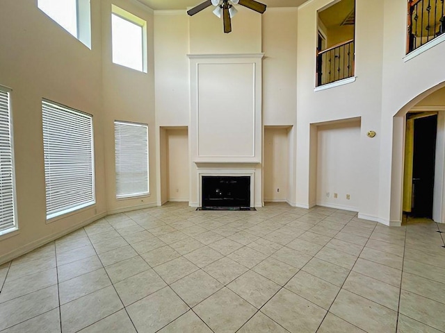 3003 Mystic Frst, Missouri City, TX 77459 - unfurnished living room featuring a high ceiling, a ceiling fan, arched walkways, light tile patterned flooring, and baseboards