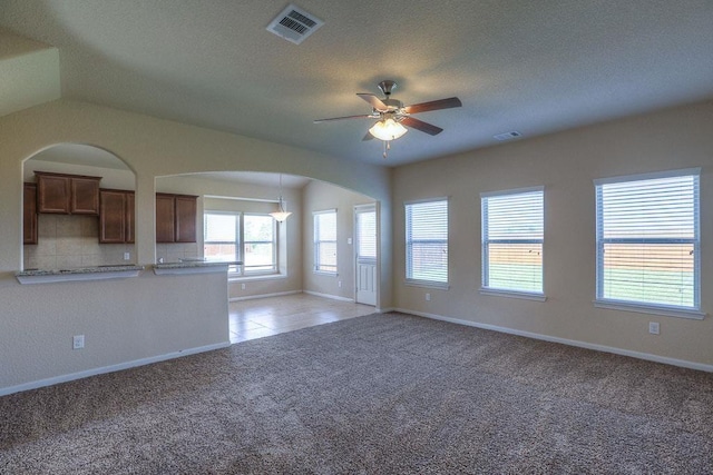 21323 Cypress Red Oak Dr, Cypress, TX 77433 - unfurnished living room with arched walkways, light colored carpet, ceiling fan, baseboards, and a textured ceiling
