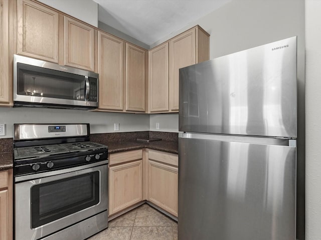 2234 Naomi St, Houston, TX 77054 - kitchen with appliances with stainless steel finishes, light brown cabinetry, light tile patterned flooring, and dark stone counters