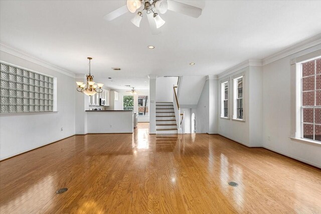 2263 Austin St, Houston, TX 77002 - unfurnished living room featuring ceiling fan, stairway, a chandelier, wood finished floors, and crown molding
